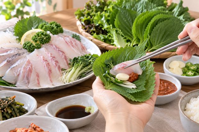싱싱한 깻잎에 생선 회와 마늘, 채소를 올려 싸 먹는 건강한 식탁