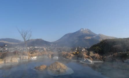 멀리 산이 보이고 물 위로 연기가 피어오르고 있다.