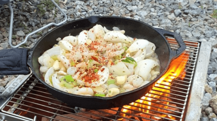 캠핑에서 화로에 감바스 요리를 하는 사진