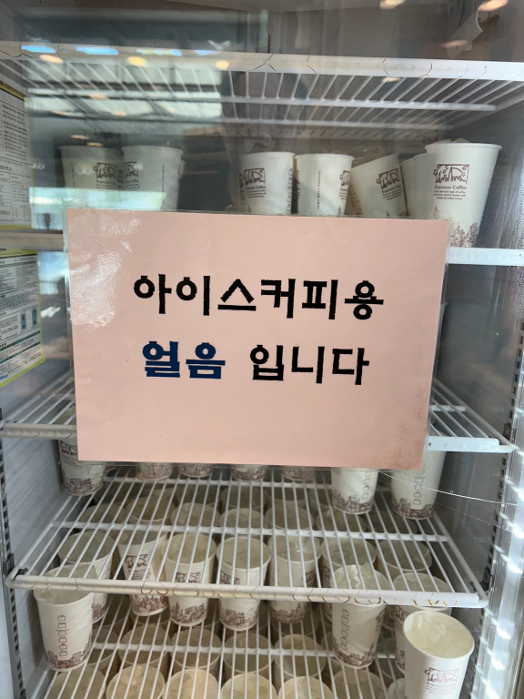 아이스커피를 위한 얼음이 들어있는 종이컵이 비치된 냉장고 이미지입니다.