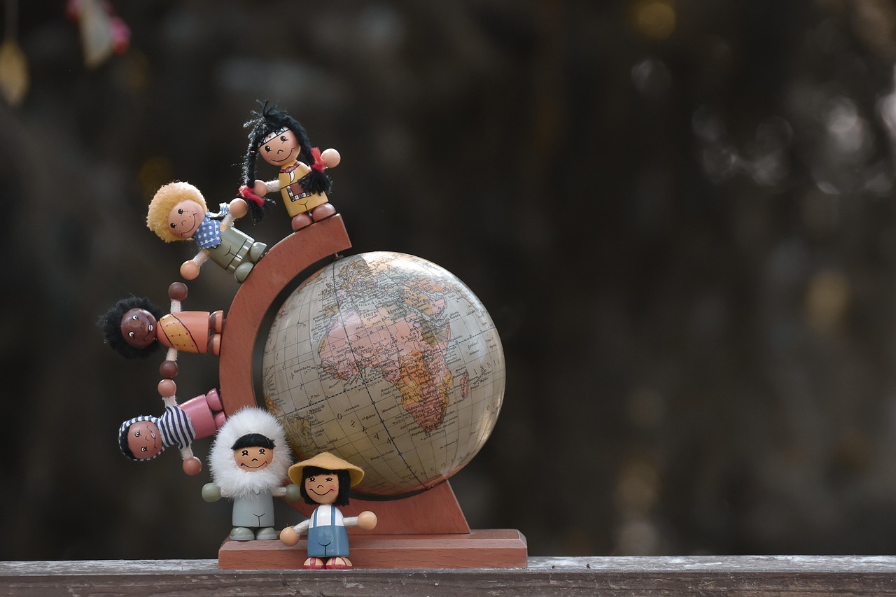 귀여운 각국의 피규어 어린이들이 지구본위를 나란히 서있는 사진.