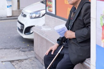 노인이-빚에-쫓겨-지팡이를-들고-건물-바닥에-앉아있는-모습