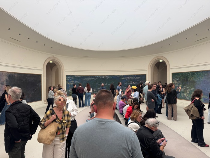 Visitors gathered inside the oval room viewing Monet Water Lilies panoramic paintings at Musée de l'Orangerie.