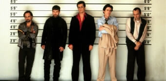 경찰서의 용의자 라인업에 서 있는 다섯 남성. 다양한 체격과 복장을 한 채 키 측정 배경 앞에 나란히 서 있다. 영화 '유주얼 서스펙트'의 유명한 장면