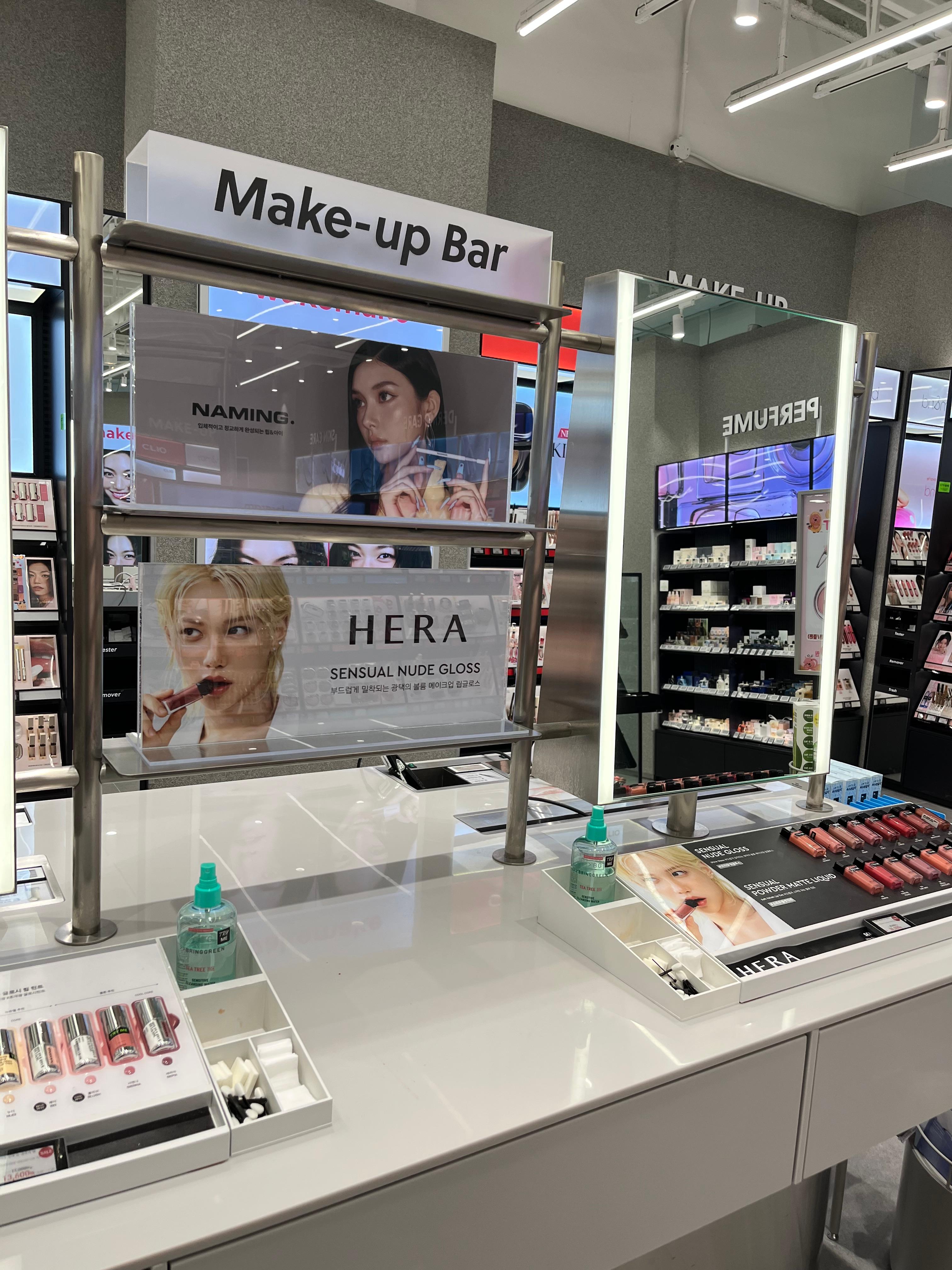 Make-up Bar at a Korean beauty store displaying popular brands like Hera and Naming, with testers and gloss products arranged for visitors to try.