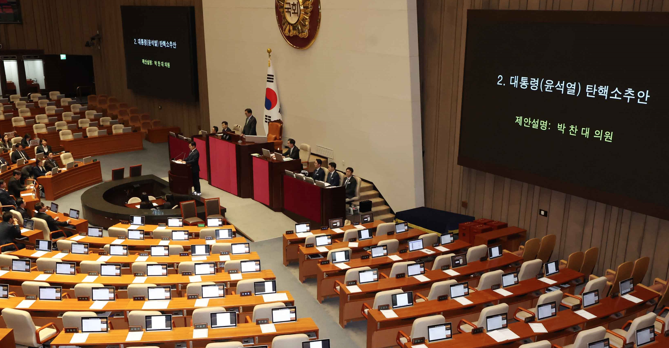 국회 본회의장 스크린에 윤석열탄핵소추안이 발의가 되어있지만 여당 좌석에는 의원들이 없이 좌석만 남아 있는 이미지