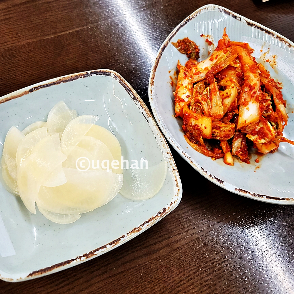 식탁위에 단무지와 김치가 그릇에 담겨있다.