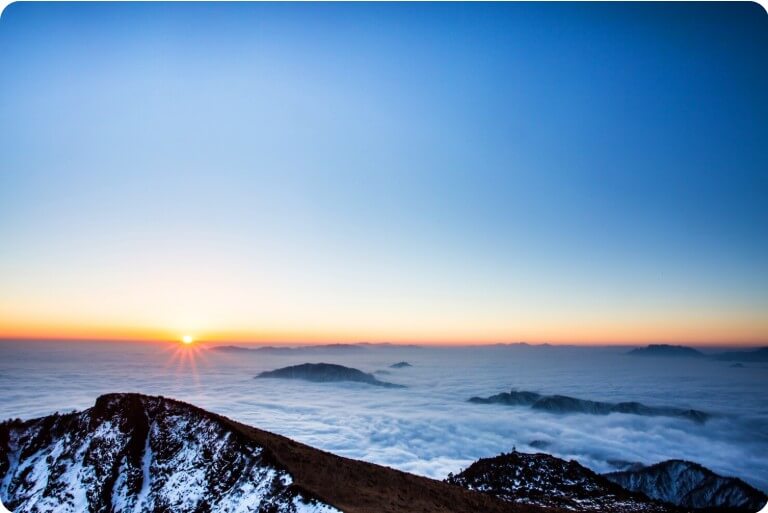 바닷가 멀리서 해가 떠오르는 모습
