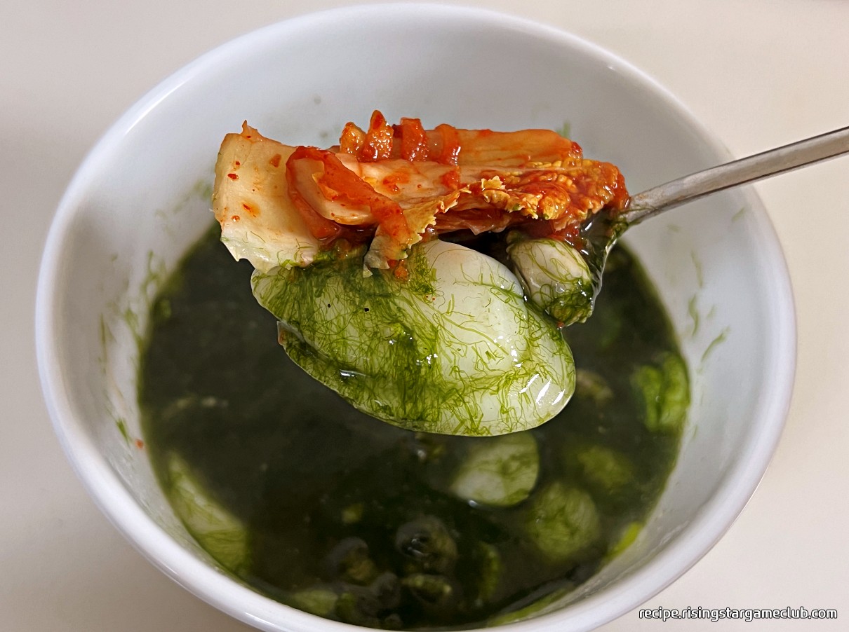 맛있는 매생이 굴 떡국 한 숟갈 위에 김치를 얹어 놓은 사진