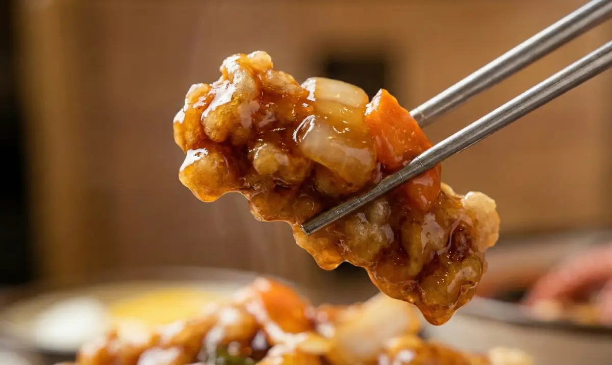 바삭하고 쫄깃한 탕수육을 젓가락으로 집어 올리는 클로즈업 사진
