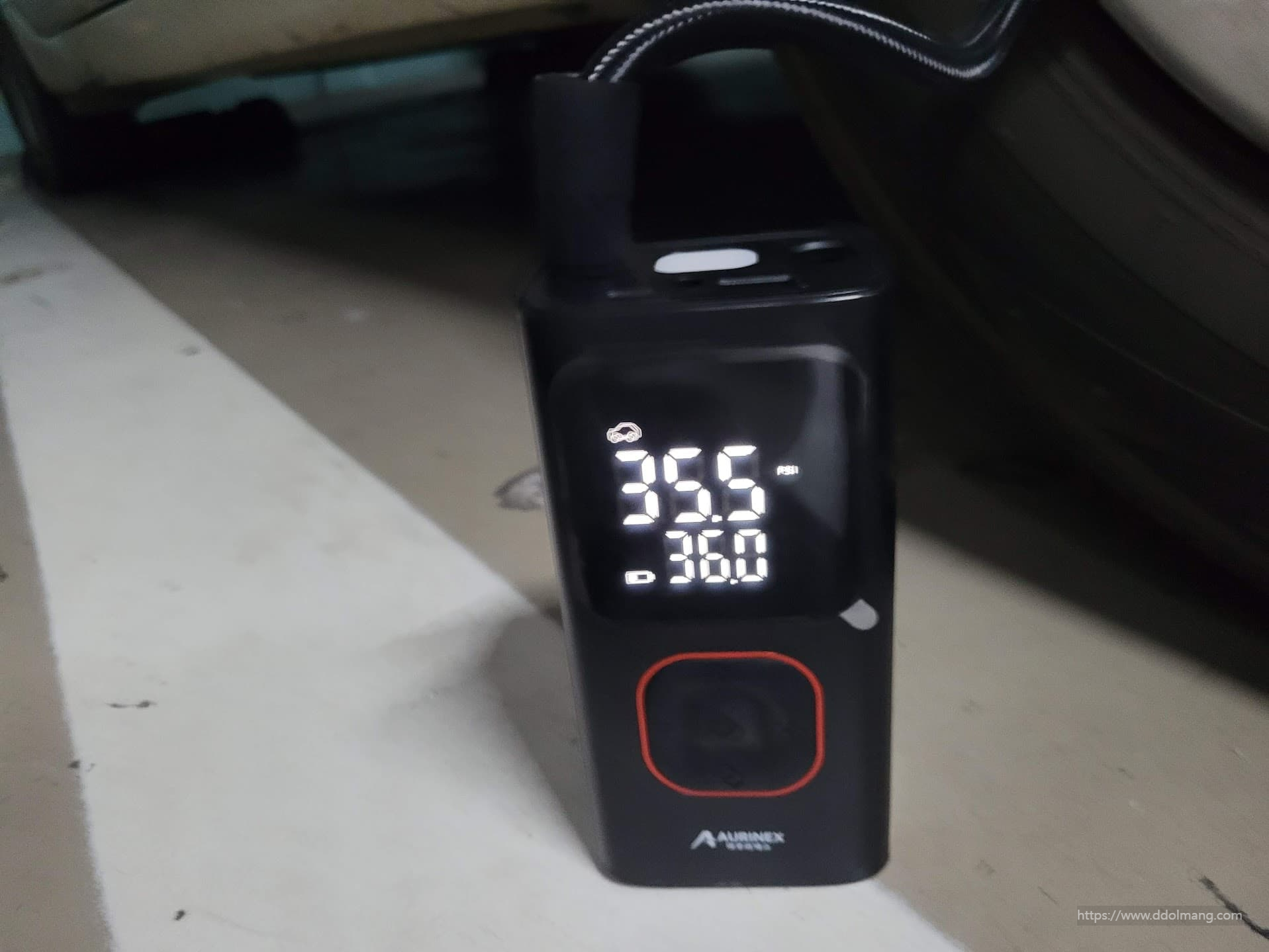 자동차에 휴대용 공기압 주입기로 공기압을 보충하는 장면