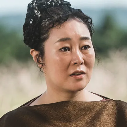 40대 여성 통통한 여성이 머리를 꼬아 위로 올리고 갈색 드레스를 입은 드라마 아라문의 검 해투악 캐릭터