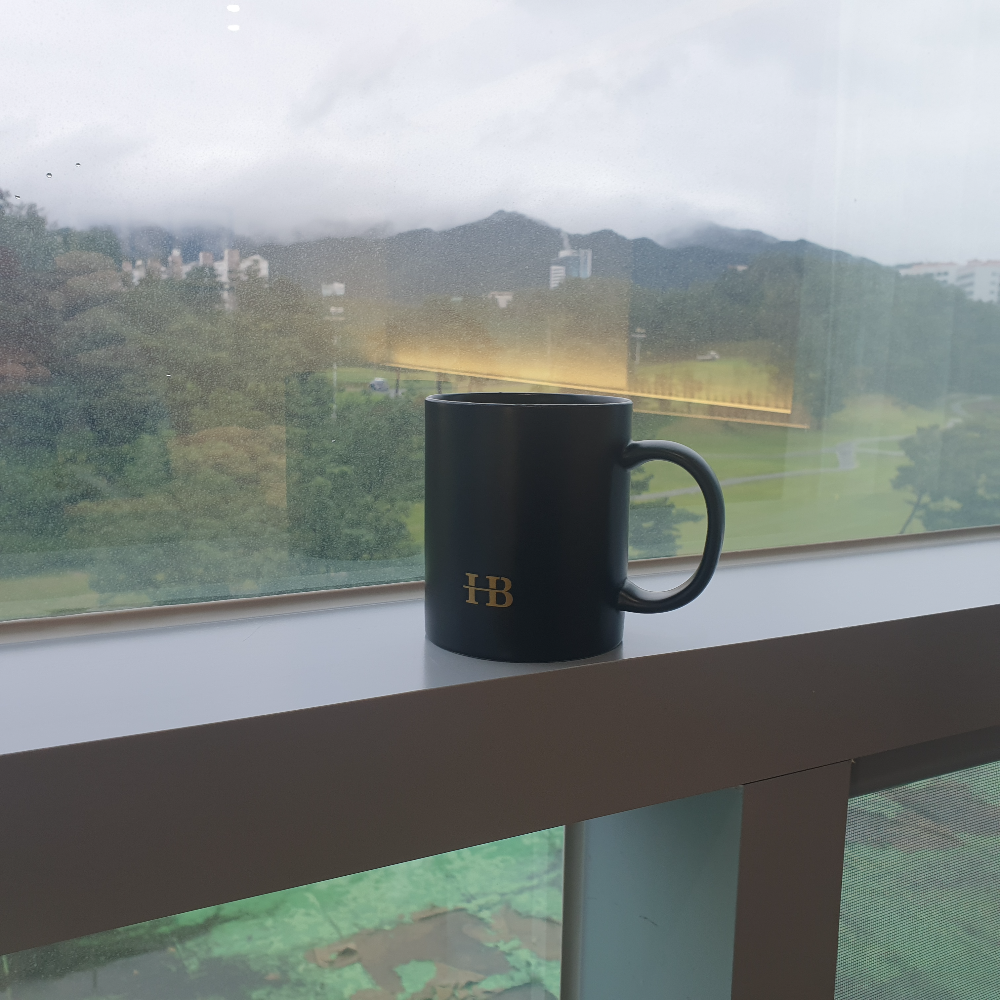 창틀에는 커피 잔이 올려져 있고 창 밖으로는 산과 골프장이 보인다.