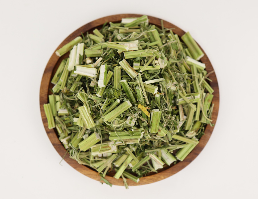 야생에서 채취를 한 익모초 풀의 줄기와 잎을 잘 세척한 후에 잘게 잘라놓은 것을 하얀 바닥 위에 고동색 나무 그릇에 가득 담아두고 찍은 사진