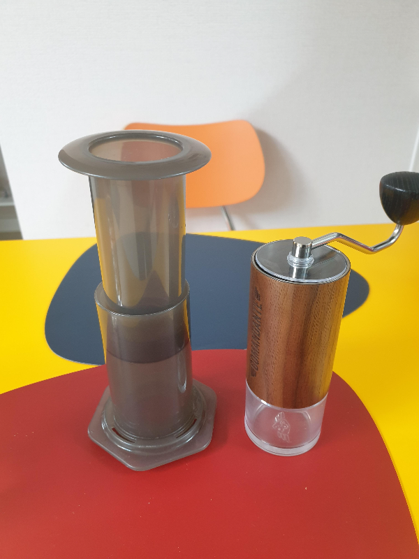 에어로프레스와 코만단테 그라인더가 테이블 위에 놓여있다.