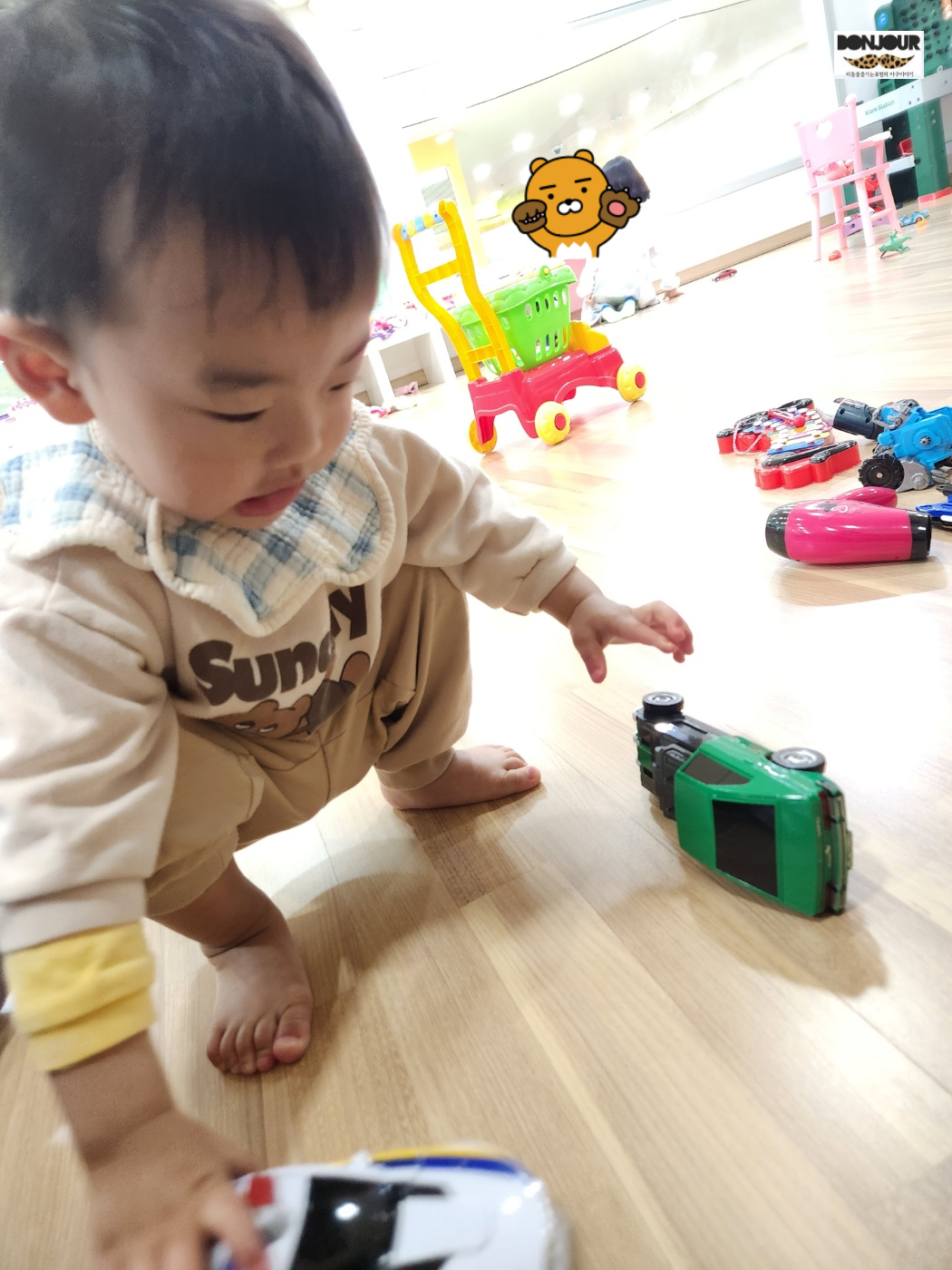 쪼그려앉아서 자동차를 들어올리는 첫째의 모습