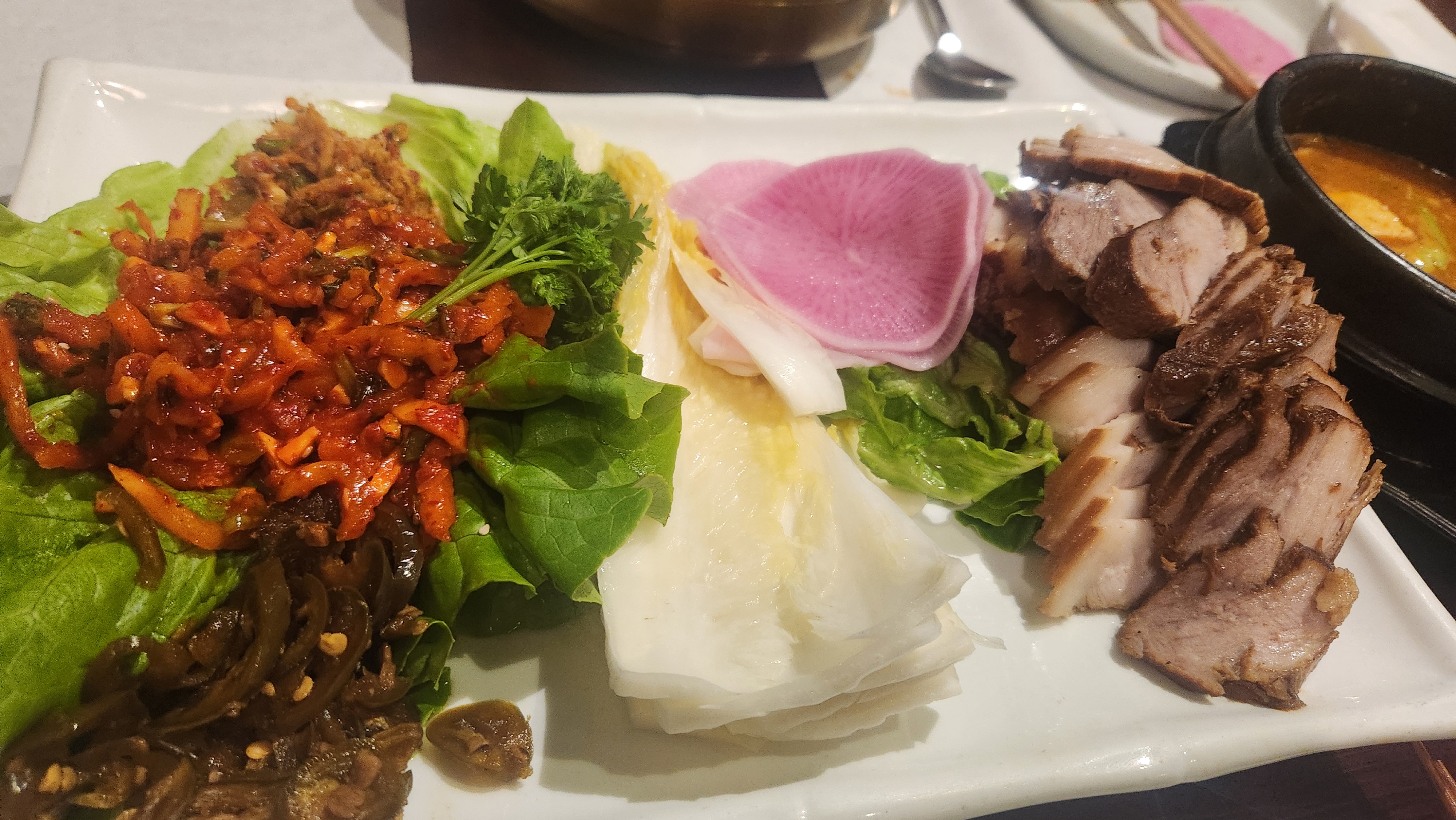 고바우 하우스 보쌈 정식 – 윤기 흐르는 수육과 무쌈, 백김치, 새우젓이 정갈하게 세팅된 한 상 이미지