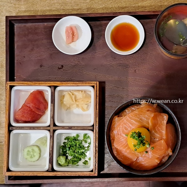 연어덮밥이 반찬들과 놓여 있어요.