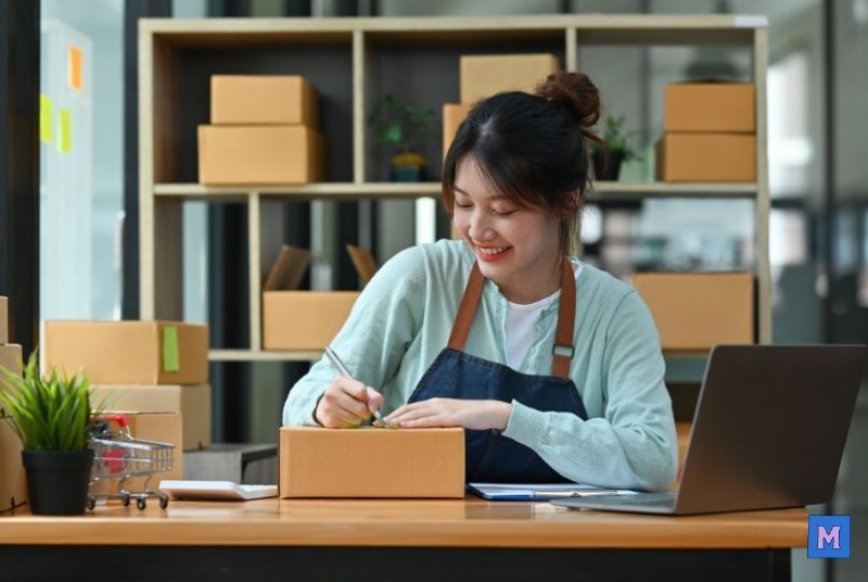 2025년 소상공인 대출을 활용하여 온라인 사업을 운영중인 여성 창업자가 택배 포장 업무를 하는 모습 via canva