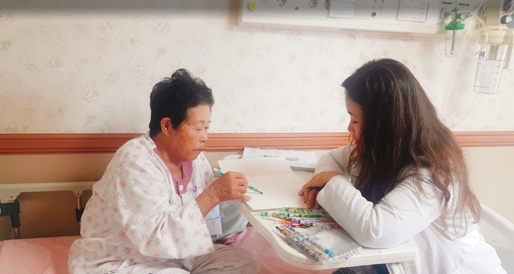 호스피스 병실에서 환자와 미술치료사가 함께 상호작용하는 모습
