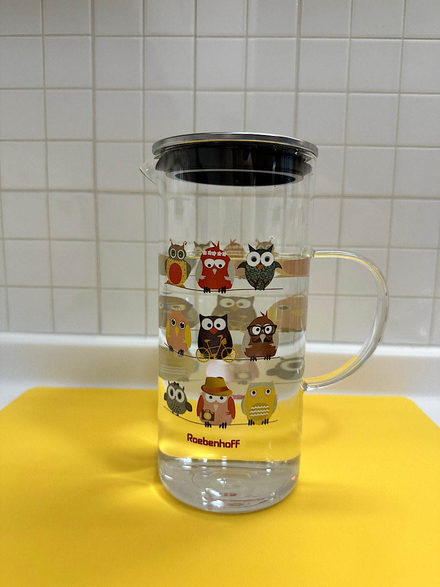 부엉이 캐릭터가 그려진 투명 유리 물병. 깨끗한 배경에 물병 디자인이 돋보임.