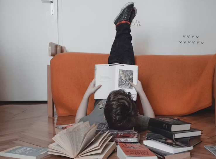 책을 읽으며 거꾸로 누워 있는 아이의 창의적인 독서 모습