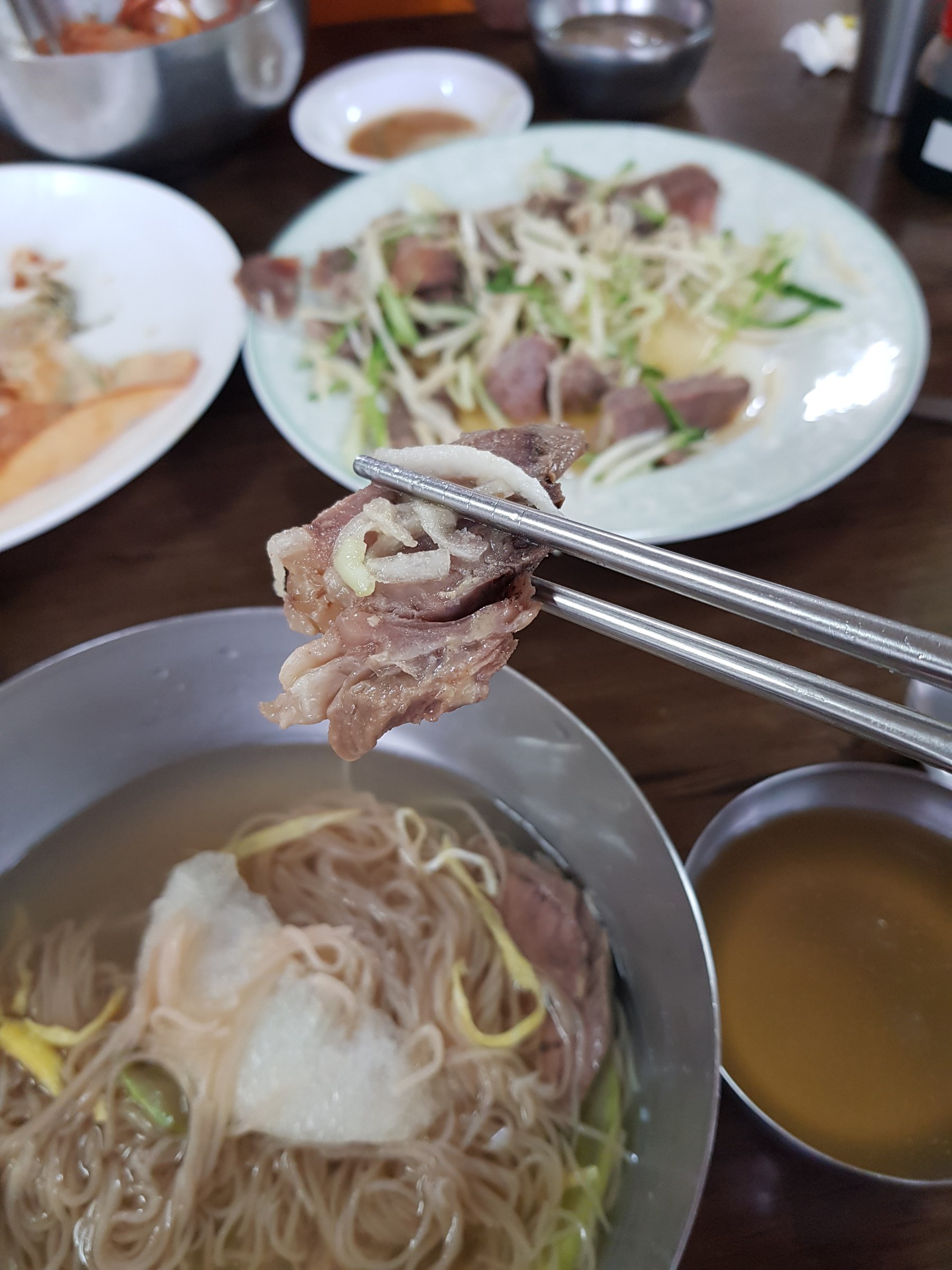 충주 삼정면옥 물냉면에 편육 한 점 젓가락으로 집은 모습