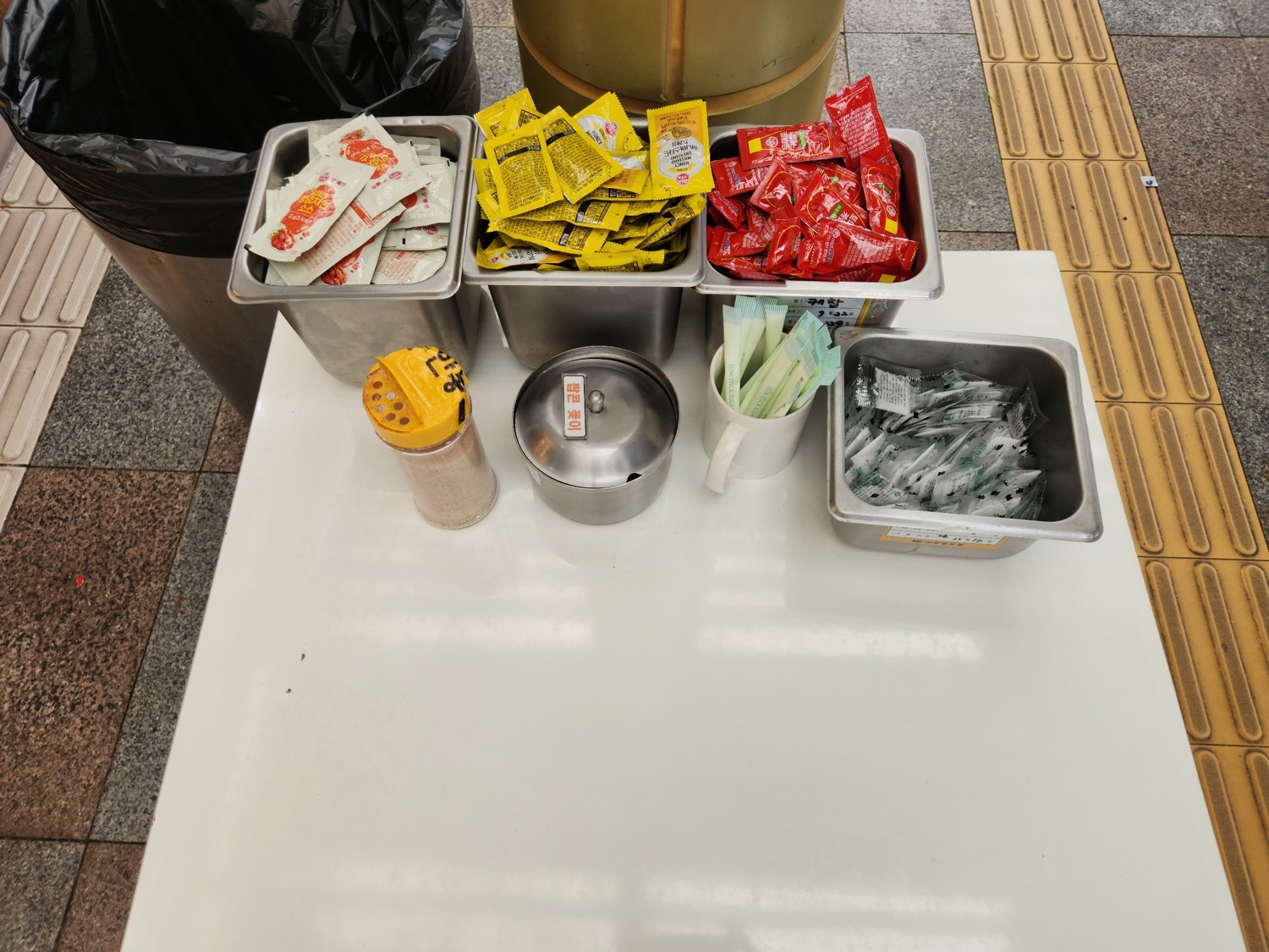 테이블 위에 1회용 케첩, 머스터드, 소금이 올려져 있다