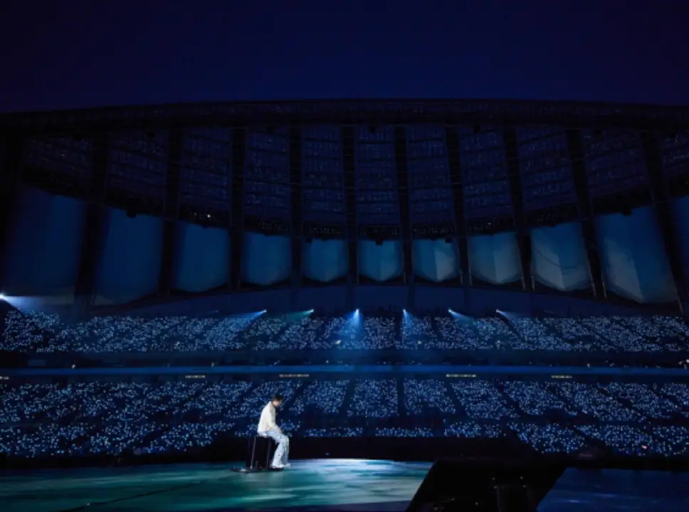 어두운 무대 반짝이는 불빛 가운데 흰옷을 입고 의자에 앉아있는 임영웅