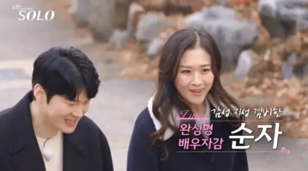 산비탈길 긴머리를 늘어뜨린채 웃으며 말하는 순자 좌측 파란 코트를 입고 웃으며 말하는 남자