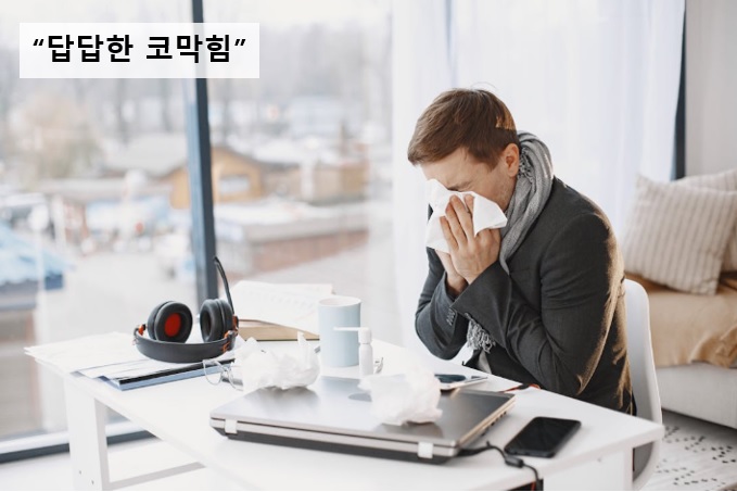 코막힘 증상으로 괴로워하며 코를 푸는 남자