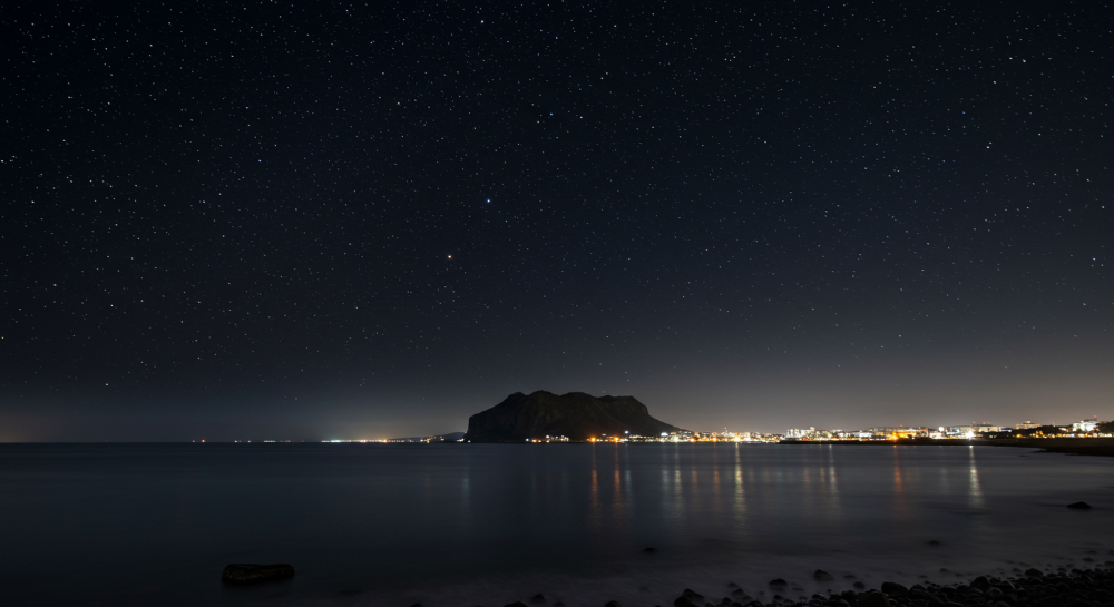 밤하늘 별빛과 도시 불빛이 어우러진 제주 밤바다 풍경