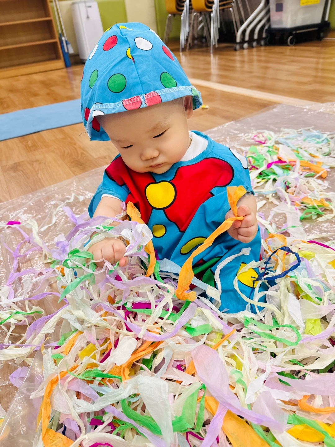 집중한 눈빛으로 습자지를 바라보며 손으로 탐색하는 9개월 아기