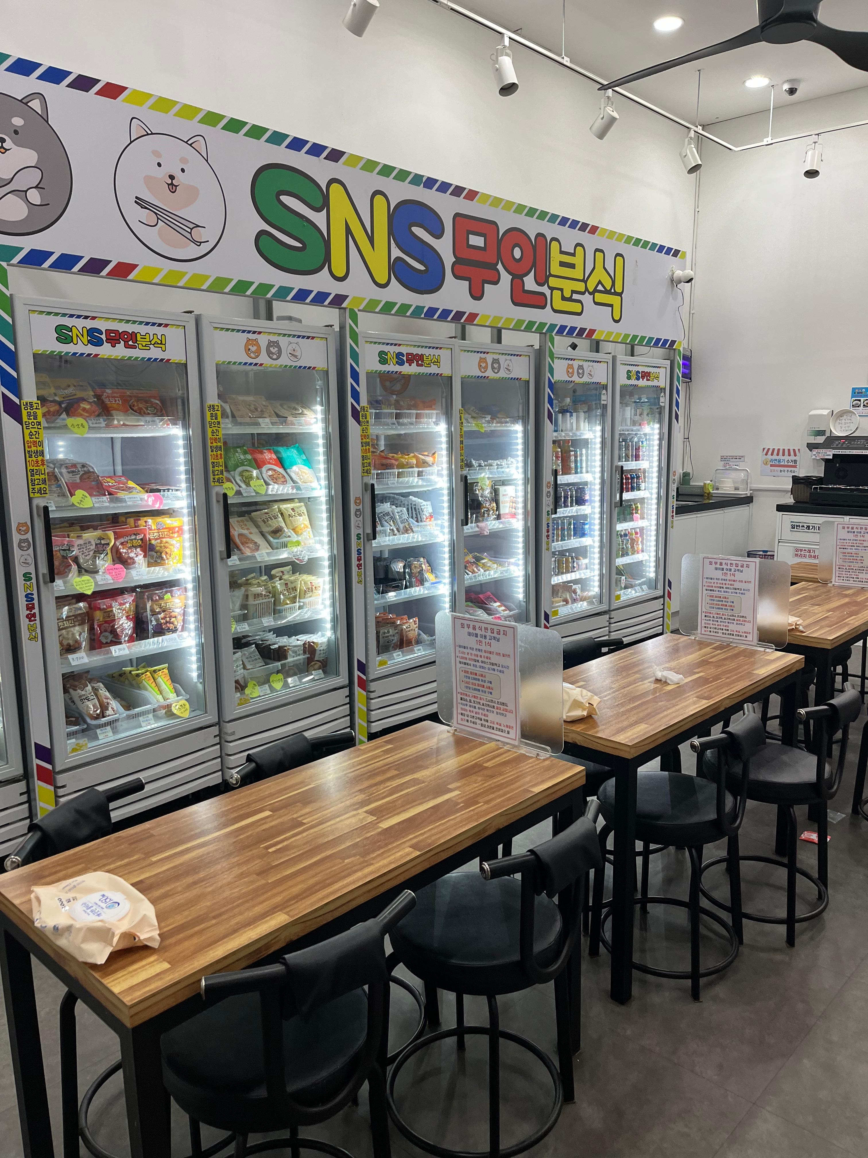 An unmanned snack store in Korea with bright refrigerators stocked with ramen, ice cream, and drinks &mdash; showing the convenience and trust-based culture behind Korea&rsquo;s self-service shops.