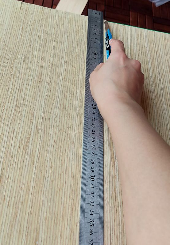 무늬목이 겹친부분에 자를 대고 칼로 그어주는 사진