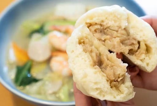 만두를 반으로 잘라 한손에 들고 있다.