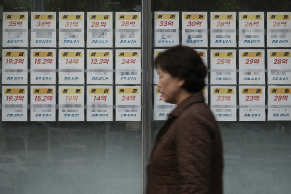 부동산 중개업소 앞을 지나는 여성