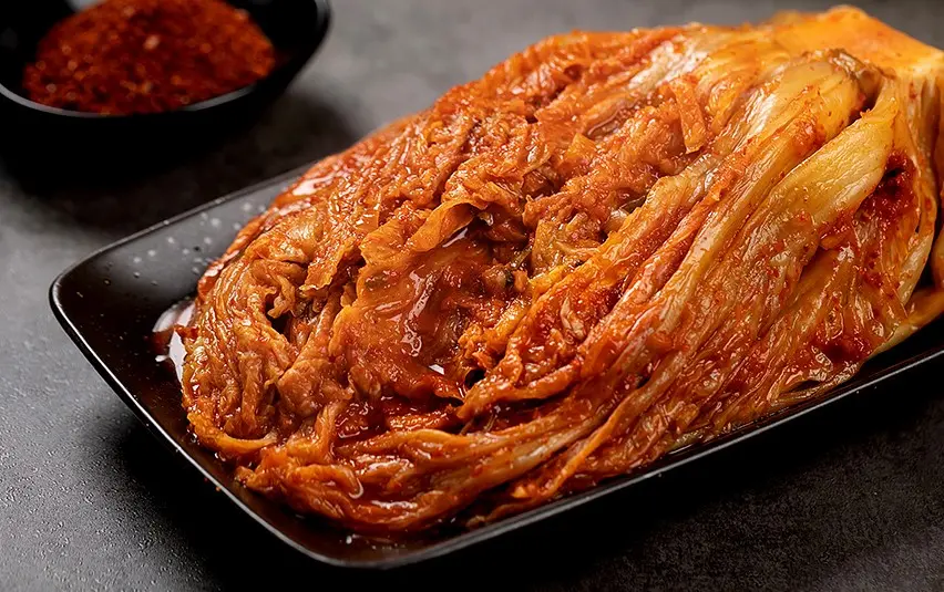 맛있게 잘 숙성 된 배추 김치 한 포기가 세라믹 접시에 담겨 있는 이미지.