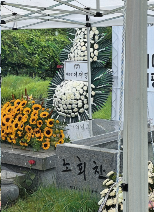 2025년 7월 19일, 이재명 대통령은 노회찬 전 의원의 7주기를 맞아 조화를 전달했습니다.
“대통령 이재명”이라고 적힌 백색 국화 화환은 마석모란공원 묘역에 별도 안내 없이 설치되었습니다. 현장에 놓인 조화는 공식 발표 없이 시민들이 촬영한 사진을 통해 공개됐습니다.