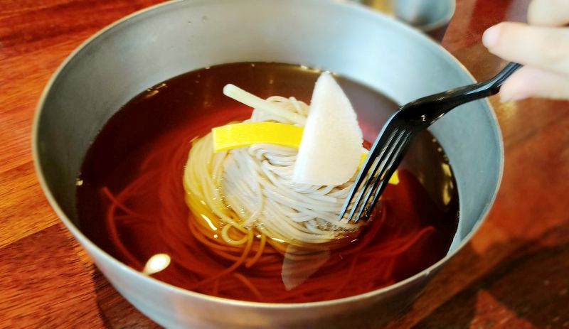 어린이 막국수 간장육수에 메밀면 고명이 올라가져있다 쿠앙이가 사진찍는데 포크를 집어 넣은사진