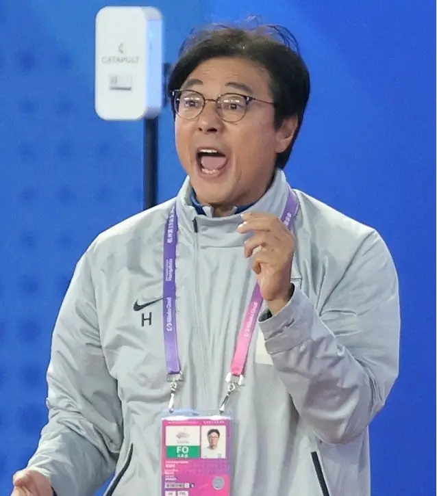 황선홍- 축구장 흰색점퍼 분홍색 목걸이 형 이름표를 목에걸고 선수들을 향해 소리지르고 있는 황선홍 감독