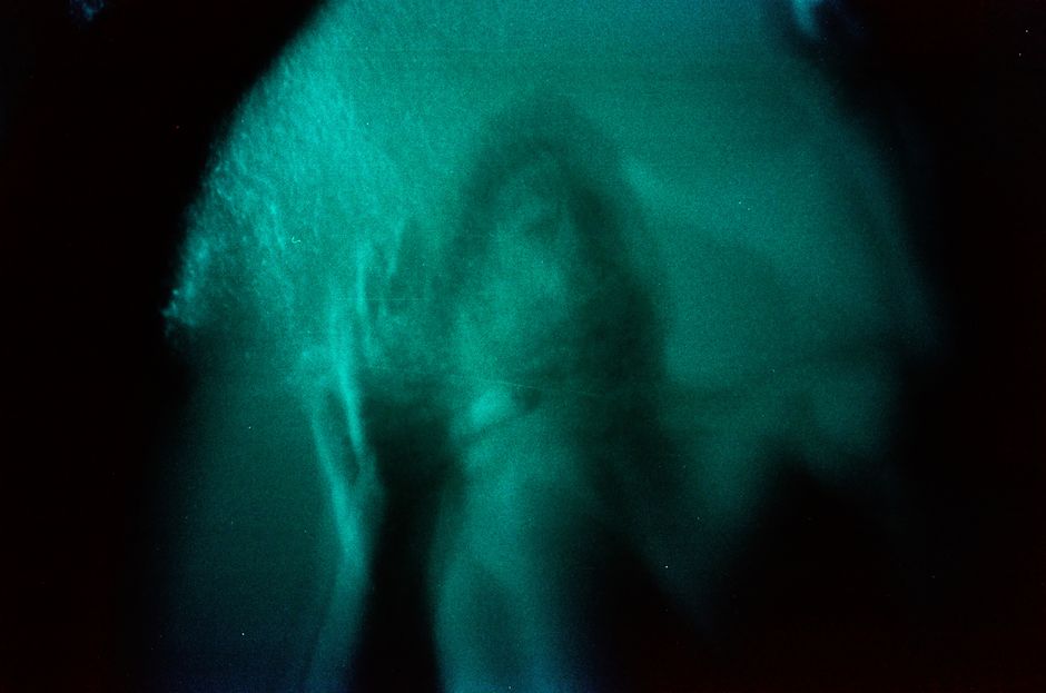 Mysterious silhouette of a person captured through blurred glass with a dark, moody tone.