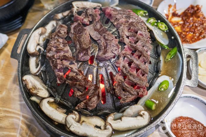 한우와 표고버섯&#44; 키조개 관자가 어우러진 음식이 불판에 담겨 있다.