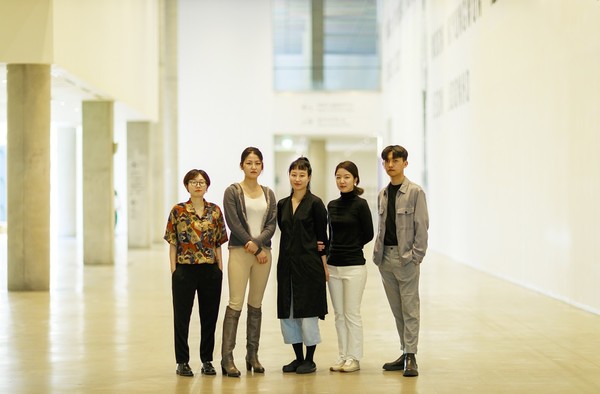 넓은 미술관에 5인의 사람이 정면을 바라보고 서있다.