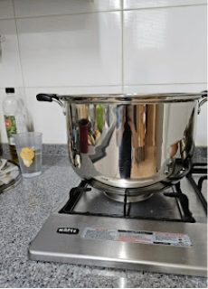 깔끔하게 관리된 주방 가스레인지 위 스테인리스 냄비에서 물이 끓고 있는 모습.