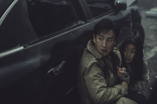 중년 남성과 여자 아이가 차 측면에 붙어 어딘가를 놀란 눈으로 바라보는 장면