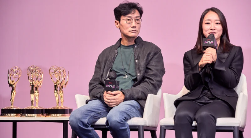 분홍색을 배경에 검은 정장을 입고 의자에 앉아 수상 소감을 말하고 있는 사이런픽처스 대표 김지연