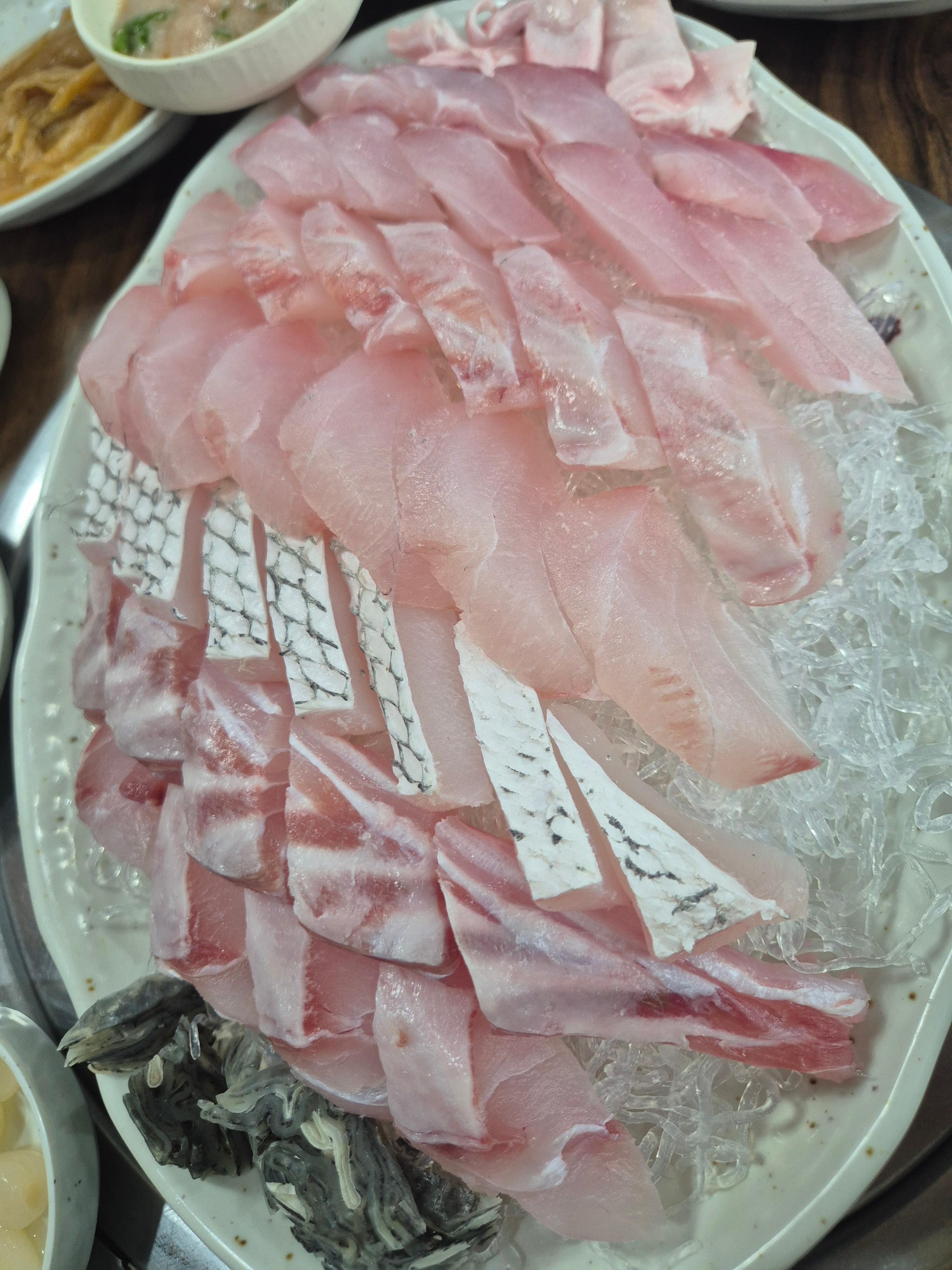 두툼하게 썬 민어회와 부레 및 껍질 부위가 담긴 접시