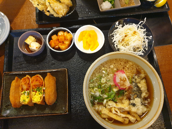 온우동 1개와 유부초밥 4개, 셀러드와 각종 반찬(깍두기, 두부, 단무지)가 보인다.