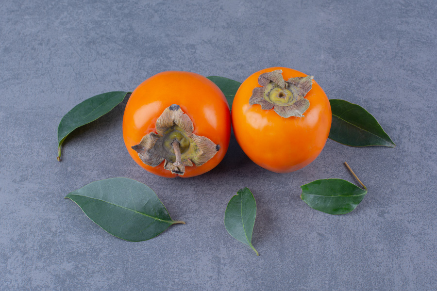 야생에서 채취를 한 감 2개를 가운데 두고 그 둘레에 감 잎사귀 6개를 놓아두고 찍은 사진